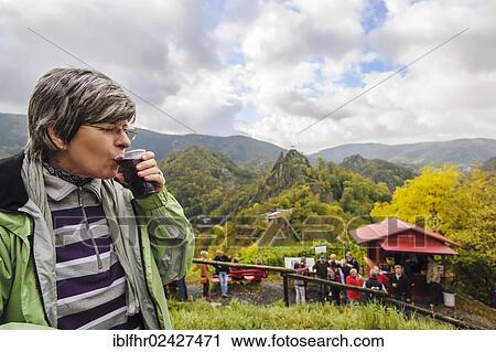 Stock Image - "A woman enjoying a cup of Federroter, fermenting new red wine, above the Rotweinwanderweg red wine trail, Altenahr, Rhineland-Palatinate, Germany, Europe". Fotosearch