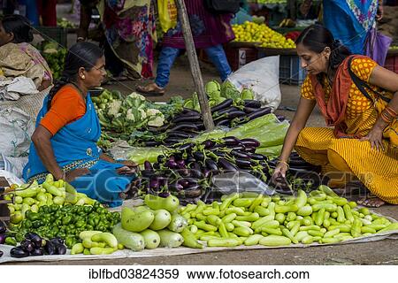 Stock Photo - "A woman is selling aubergines, peppers, cauliflowers and cucumbers at the weekly vegetable market, Nasik, Maharashtra, India, Asia". Fotosearch