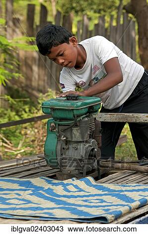"A young Khmer starting the engine of the bamboo train, a motorized bamboo platform that travels several kilometers on the railway tracks between Phnom Penh and Battambang, Battambang, Cambodia, Southeast Asia, Asia" View Large Photo Image Stock Image - "A young Khmer starting the engine of the bamboo train, a motorized bamboo platform that travels several kilometers on the railway tracks between Phnom Penh and Battambang, Battambang, Cambodia, Southeast Asia, Asia". Fotosearch