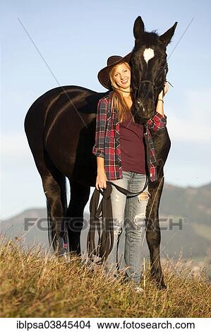 "A young woman and a black Hanoverian horse standing on a mountain meadow in autumn, North Tyrol, Austria, Europe" View Large Photo Image Picture - "A young woman and a black Hanoverian horse standing on a mountain meadow in autumn, North Tyrol, Austria, Europe". Fotosearch