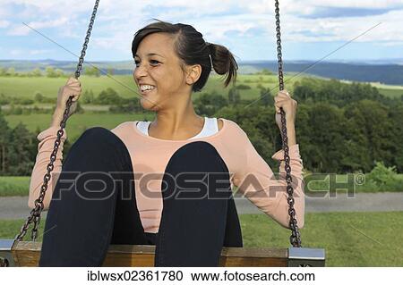 "A young woman of Indonesian descent sitting on a swing, Baden-Wuerttemberg, Germany, Europe, PublicGround, Europe" View Large Photo Image Stock Image - "A young woman of Indonesian descent sitting on a swing, Baden-Wuerttemberg, Germany, Europe, PublicGround, Europe". Fotosearch