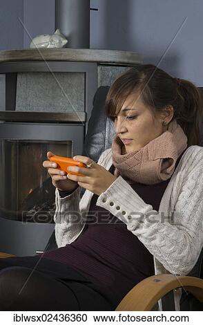 "A young woman of Indonesian origin is sitting in front of a wood burner working on a smartphone, Germany, Europe" View Large Photo Image Stock Image - "A young woman of Indonesian origin is sitting in front of a wood burner working on a smartphone, Germany, Europe". Fotosearch