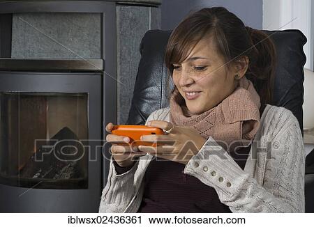 "A young woman of Indonesian origin is sitting in front of a wood burner working on a smartphone, Germany, Europe" View Large Photo Image Stock Image - "A young woman of Indonesian origin is sitting in front of a wood burner working on a smartphone, Germany, Europe". Fotosearch