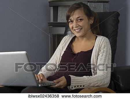 "A young woman of Indonesian origin is sitting in front of a wood burner working on a laptop computer, Germany, Europe" View Large Photo Image Stock Photo - "A young woman of Indonesian origin is sitting in front of a wood burner working on a laptop computer, Germany, Europe". Fotosearch