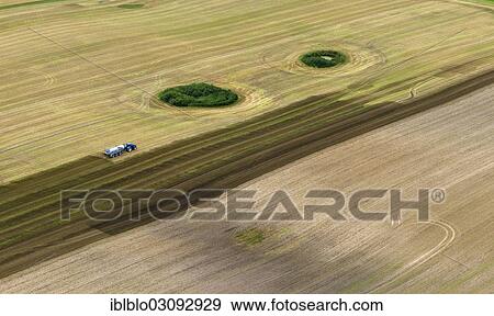 Stock Photo - "Aerial view, harvested field with forest islands, tractor spreading slurry, Gross Kedingshagen, Kramerhof, Mecklenburg-Western Pomerania, Germany, Europe". Fotosearch