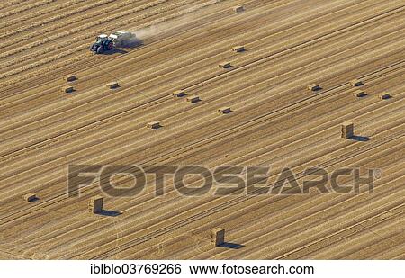 Stock Photograph - "Aerial view, straw bales and tractor in a cornfield, North Rhine-Westphalia, Germany, Europe". Fotosearch
