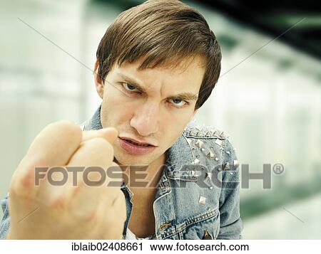 Stock Image - "Aggressive young man wearing a studded denim jacket, portrait". Fotosearch