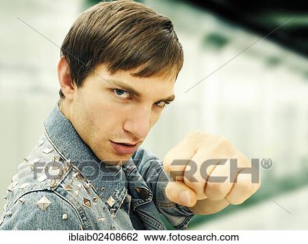 Stock Image - "Aggressive young man wearing a studded denim jacket, portrait". Fotosearch