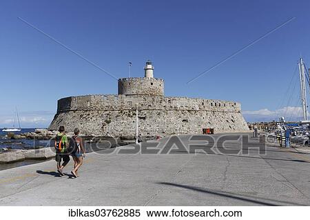 "Agios Nikolaos fortress, two tourists in front, Mandraki Harbour, Rhodes, Rhodes island, Dodecanese, Greece, Europe" View Large Photo Image Stock Photography - "Agios Nikolaos fortress, two tourists in front, Mandraki Harbour, Rhodes, Rhodes island, Dodecanese, Greece, Europe". Fotosearch