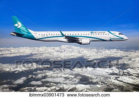 Stock Image - "Air Dolomiti Embraer ERJ-195LR in flight over snow-covered mountains, Dolomites, Italy, Europe". Fotosearch