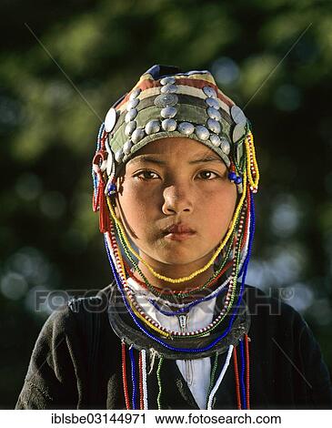 Stock Image - "Akha girl with traditional clothing and headdress, portrait, Chiang Rai Province, Northern Thailand, Thailand, Asia". Fotosearch