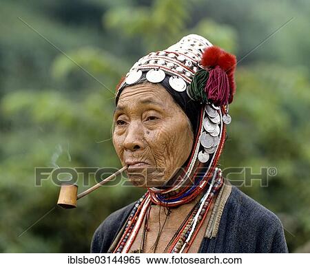 Stock Photography - "Akha woman with a pipe, a traditional dress and headdress with silver coins, portrait, Chiang Rai Province, Northern Thailand, Thailand, Asia". Fotosearch