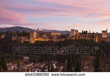 Stock Image - "Alhambra palace at dusk, on the right the Alcazaba, in the foreground the Moorish quarter Albaicin, the Sierra Nevada at the back, Granada, Granada province, Andalusia, Spain, Europe". Fotosearch