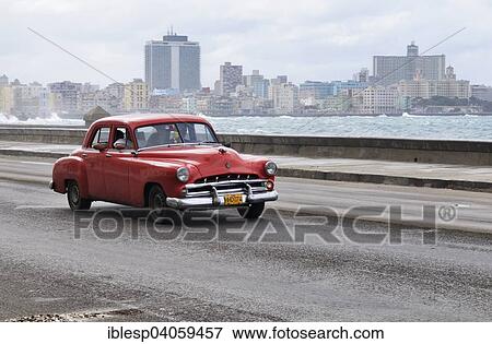 Stock Photo - "American vintage car travelling on the Malecon, the modern Vedado district at the back, Centro Habana, Havana, Ciudad de La Habana, Cuba, North America". Fotosearch