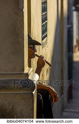 "An elderly Cuban sitting on a doorstep in the evening light, smoking a cigar, Trinidad, Sancti Spiritus Province, Cuba, North America" View Large Photo Image Picture - "An elderly Cuban sitting on a doorstep in the evening light, smoking a cigar, Trinidad, Sancti Spiritus Province, Cuba, North America". Fotosearch