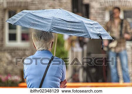 "An elderly woman holding an umbrella, Paffendorf, North Rhine-Westphalia, Germany, Europe" View Large Photo Image Stock Photo - "An elderly woman holding an umbrella, Paffendorf, North Rhine-Westphalia, Germany, Europe". Fotosearch