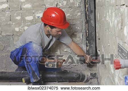 Stock Photography - "An electrician, systems mechanic for sanitary engineering, heating and air conditioning, installing a sewer pipe, driving a slot for a sewer pipe, refurbishment, Baden-Wuerttemberg, Germany, Europe". Fotosearch