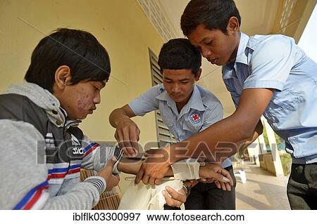 "Applying a pressure bandage, training of young people from the community to become first aid workers by the Red Cross, Tropeng Village, Bathi District, Takeo Province, Cambodia, Asia" View Large Photo Image Stock Photo - "Applying a pressure bandage, training of young people from the community to become first aid workers by the Red Cross, Tropeng Village, Bathi District, Takeo Province, Cambodia, Asia". Fotosearch