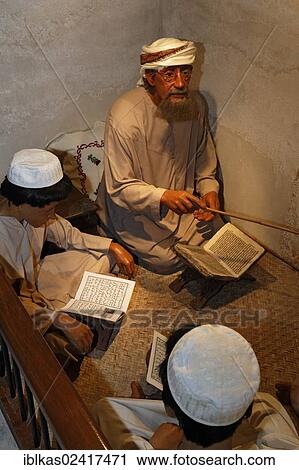 Stock Image - Arabic tutor teaching students while sitting on the ground, life-size figures, Al-Ahmadiya School Museum, Dubai, United Arab Emirates, Middle East, Asia. Fotosearch