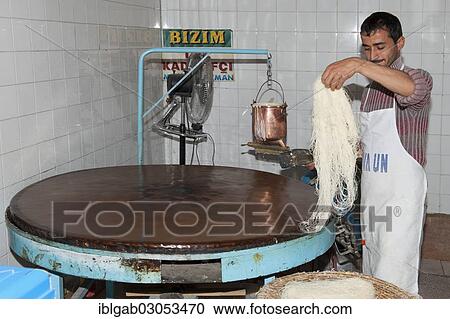 "Artisan pouring a continuous stream of highly-fluid dough on a hot plate to prepare the Tel Kadayif or Angels hair, used for Kunefe dessert, Antioch market, Antakya, Hatay Province, Turkey, Asia" View Large Photo Image Stock Image - "Artisan pouring a continuous stream of highly-fluid dough on a hot plate to prepare the Tel Kadayif or Angels hair, used for Kunefe dessert, Antioch market, Antakya, Hatay Province, Turkey, Asia". Fotosearch