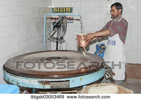 Stock Photo - "Artisan pouring a continuous stream of highly-fluid dough on a hot plate to prepare the Tel Kadayif or Angels hair, used for Kunefe dessert, Antioch market, Antakya, Hatay Province, Turkey, Asia". Fotosearch