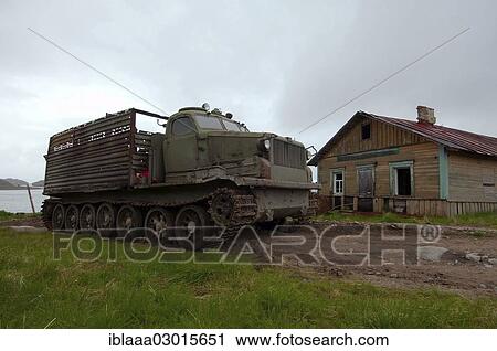 Stock Image - "AT-T caterpillar all-terrain vehicle in front of a derelict house in a rural locality, Dalniye Zelentsy, Kola Peninsula, Kolsky District, Murmansk Oblast, Russia, Europe". Fotosearch