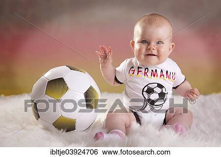 "Baby girl, 7 months, wearing a Germany football jersey with a football, German colours at the back" View Large Photo Image Stock Photograph - "Baby girl, 7 months, wearing a Germany football jersey with a football, German colours at the back". Fotosearch