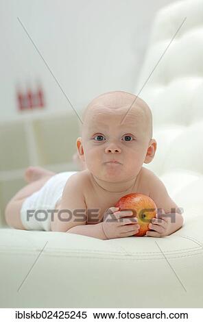 Baby lying on his stomach with an apple View Large Photo Image Stock Photography - Baby lying on his stomach with an apple. Fotosearch