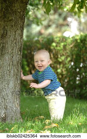 "Baby, one year, standing by a tree" View Large Photo Image Picture - "Baby, one year, standing by a tree". Fotosearch
