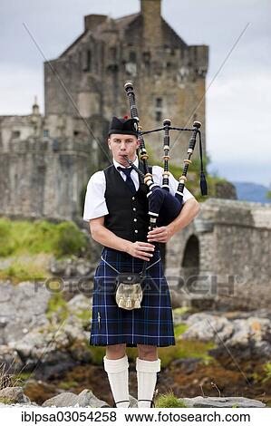 Stock Photo - "Bagpiper standing in front of Eilean Donan Castle, Loch Alsh, Scotland, United Kingdom, Europe". Fotosearch