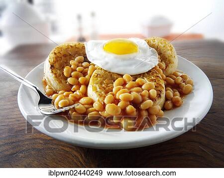 Baked beans on crumpets with fried egg on top View Large Photo Image Stock Photo - Baked beans on crumpets with fried egg on top. Fotosearch