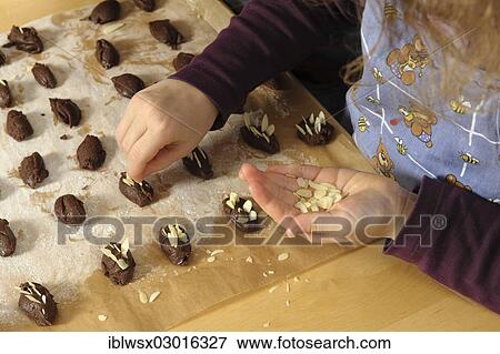 "Baking Christmas cookies, girl, 6, putting almonds into the dough for hedgehog biscuits, Mundingen, Emmendingen |Emmendingen|, Baden-Wurttemberg, Germany, Europe" View Large Photo Image Stock Photo - "Baking Christmas cookies, girl, 6, putting almonds into the dough for hedgehog biscuits, Mundingen, Emmendingen |Emmendingen|, Baden-Wurttemberg, Germany, Europe". Fotosearch