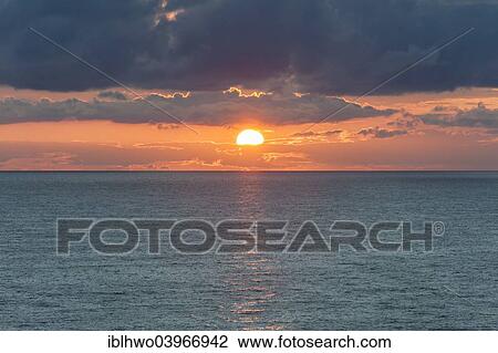 Stock Image - "Baltic Sea at sunset, container ship at the back, clouds, off the island of Gotland, Sweden, Europe". Fotosearch
