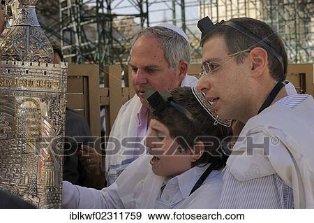 Stock Photo - "Bar Mitzvah, Jewish coming of age ritual, with phylacteries, tefillin and kippah at the Wailing Wall or Western Wall, boy reading from the Torah scrolls, Muslim Quarter, Jerusalem, Israel, Middle East, Southwest Asia, Asia". Fotosearch