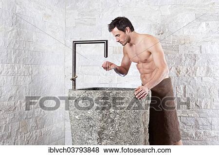 Bare-chested man standing at a water fountain in a spa complex View Large Photo Image Stock Photo - Bare-chested man standing at a water fountain in a spa complex. Fotosearch