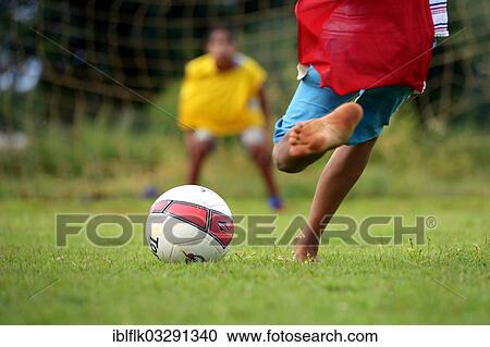 Stock Image - "Barefoot boy taking a penalty kick, social project in a favela, Poxoreo, Mato Grosso, Brazil, South America". Fotosearch