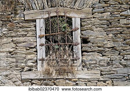 Stock Image - "Barred, overgrown windows of a deserted house, village of Begos, Val d'Aran, Aran Valley, Pyrenees, Lleida province, Catalonia, Spain, Europe, PublicGround, Europe". Fotosearch