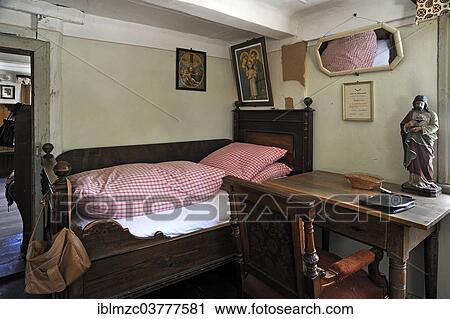 Stock Image - "Bed and a desk in the lower bedroom, furnished as in 1920, in a farmhouse originally from Kleinrinderfeld, built in 1779, relocated to the Franconian Open Air Museum in Bad Windsheim, Middle Franconia, Bavaria, Germany, Europe". Fotosearch