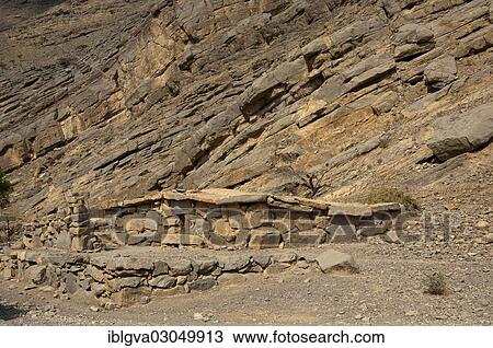 Stock Image - "Bedouin stone house matching in colour and texture to the foot of a cliff in the mountains of Musandam, Musandam Governorate, Oman, Asia". Fotosearch