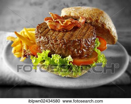 Beef burger with bacon in a wholemeal bun with salad and french fries View Large Photo Image Stock Image - Beef burger with bacon in a wholemeal bun with salad and french fries. Fotosearch