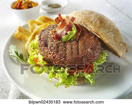 Beef burger with bacon in a wholemeal bun with salad and french fries View Large Photo Image Stock Image - Beef burger with bacon in a wholemeal bun with salad and french fries. Fotosearch