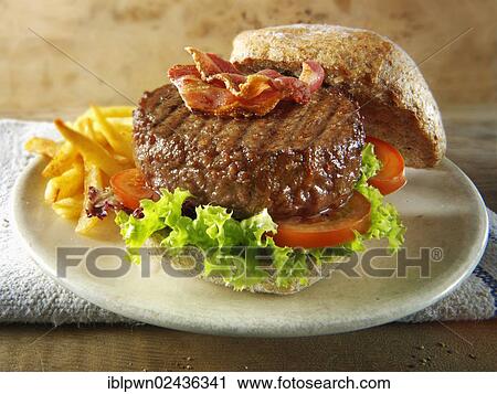 Beef burger with bacon in a wholemeal bun with salad and french fries View Large Photo Image Stock Image - Beef burger with bacon in a wholemeal bun with salad and french fries. Fotosearch