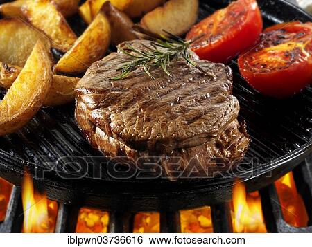 Stock Photograph - Beef fillet steaks and chips being pan fried on a BBQ. Fotosearch