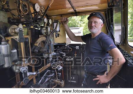 "Bernd Roschach, train driver chairman of the Acher Valley Railway Society, standing in a locomotive of the Acher Valley Railway from 1928 in Ottenhoefen station, Ottenhofen im Schwarzwald, Black Forest, Baden-Wurttemberg, Germany, Europe" View Large Photo Image Stock Image - "Bernd Roschach, train driver chairman of the Acher Valley Railway Society, standing in a locomotive of the Acher Valley Railway from 1928 in Ottenhoefen station, Ottenhofen im Schwarzwald, Black Forest, Baden-Wurttemberg, Germany, Europe". Fotosearch