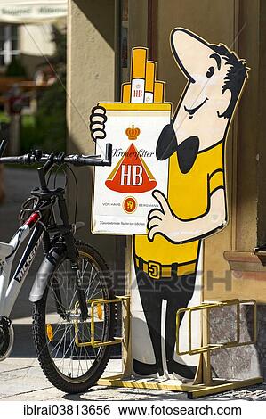 "Bicycle stand with the HB-Mannchen advertising character, HB brand of cigarettes, Mittenwald, Upper Bavaria, Bavaria, Germany, Europe" View Large Photo Image Stock Photograph - "Bicycle stand with the HB-Mannchen advertising character, HB brand of cigarettes, Mittenwald, Upper Bavaria, Bavaria, Germany, Europe". Fotosearch