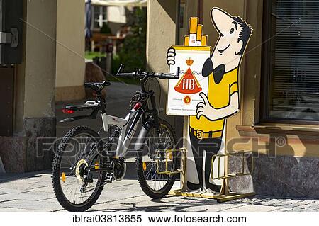 "Bicycle stand with the HB-Mannchen advertising character, HB brand of cigarettes, Mittenwald, Upper Bavaria, Bavaria, Germany, Europe" View Large Photo Image Stock Photography - "Bicycle stand with the HB-Mannchen advertising character, HB brand of cigarettes, Mittenwald, Upper Bavaria, Bavaria, Germany, Europe". Fotosearch