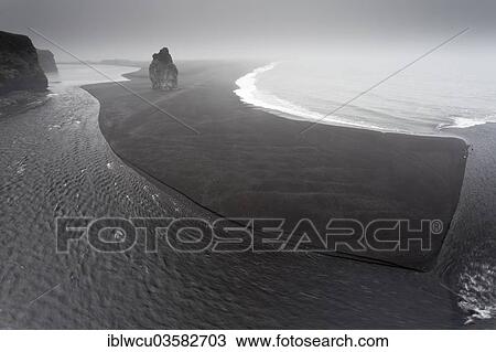 "Black lava beach with a basalt rock, shaped by the onset of the low tide and tidal flowes, in the fog, view from the Dyrholaey bird rock, Vik i Myrdal, Suourland, Iceland, Europe" View Large Photo Image Stock Image - "Black lava beach with a basalt rock, shaped by the onset of the low tide and tidal flowes, in the fog, view from the Dyrholaey bird rock, Vik i Myrdal, Suourland, Iceland, Europe". Fotosearch