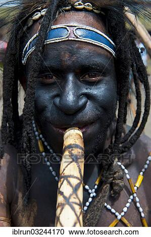 Stock Image - "Black painted and decorated man during the traditional Sing Sing in the highlands, Enga, Highlands, Papua New Guinea, Oceania". Fotosearch