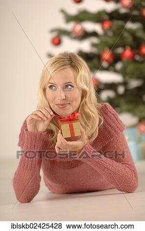 "Blonde woman, 20-30, holding a golden gift box, Christmas ambience" View Large Photo Image Stock Photo - "Blonde woman, 20-30, holding a golden gift box, Christmas ambience". Fotosearch