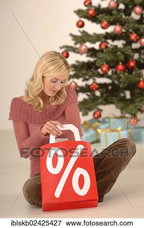 "Blonde woman, 20-30, holding a shopping bag with a percent sign, Christmas ambience" View Large Photo Image Stock Photo - "Blonde woman, 20-30, holding a shopping bag with a percent sign, Christmas ambience". Fotosearch